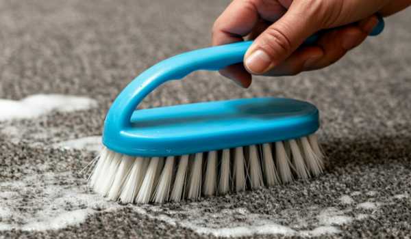 Scrubbing moldy outdoor carpet using a soft-bristle brush and baking soda for stubborn spots.